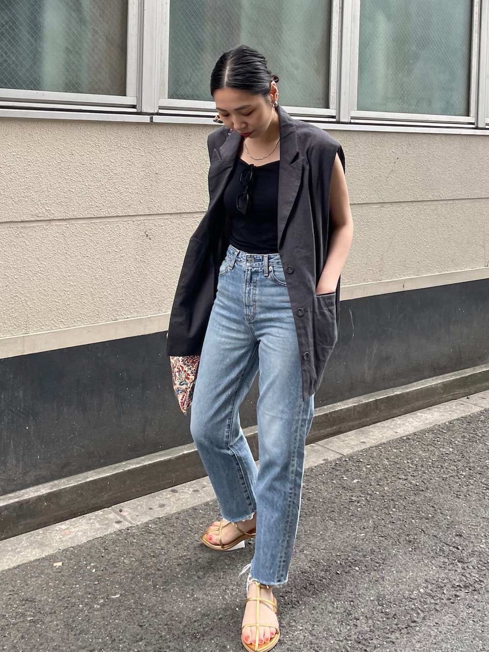 ブルー系のデニムパンツ、ゴールド系のサンダル、ホワイト系のショルダーバッグを着用したレディースの春コーディネートの2枚目の写真