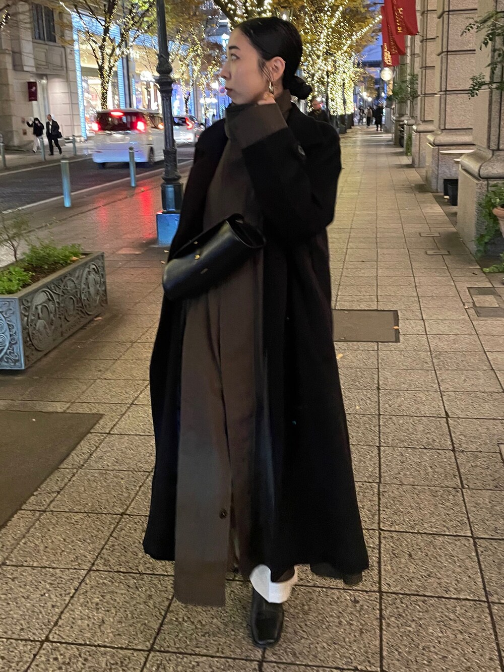 ブラック系のブーツ、ブラック系のチェスターコート、ブラック系のショルダーバッグを着用したレディースの冬コーディネートの3枚目の写真