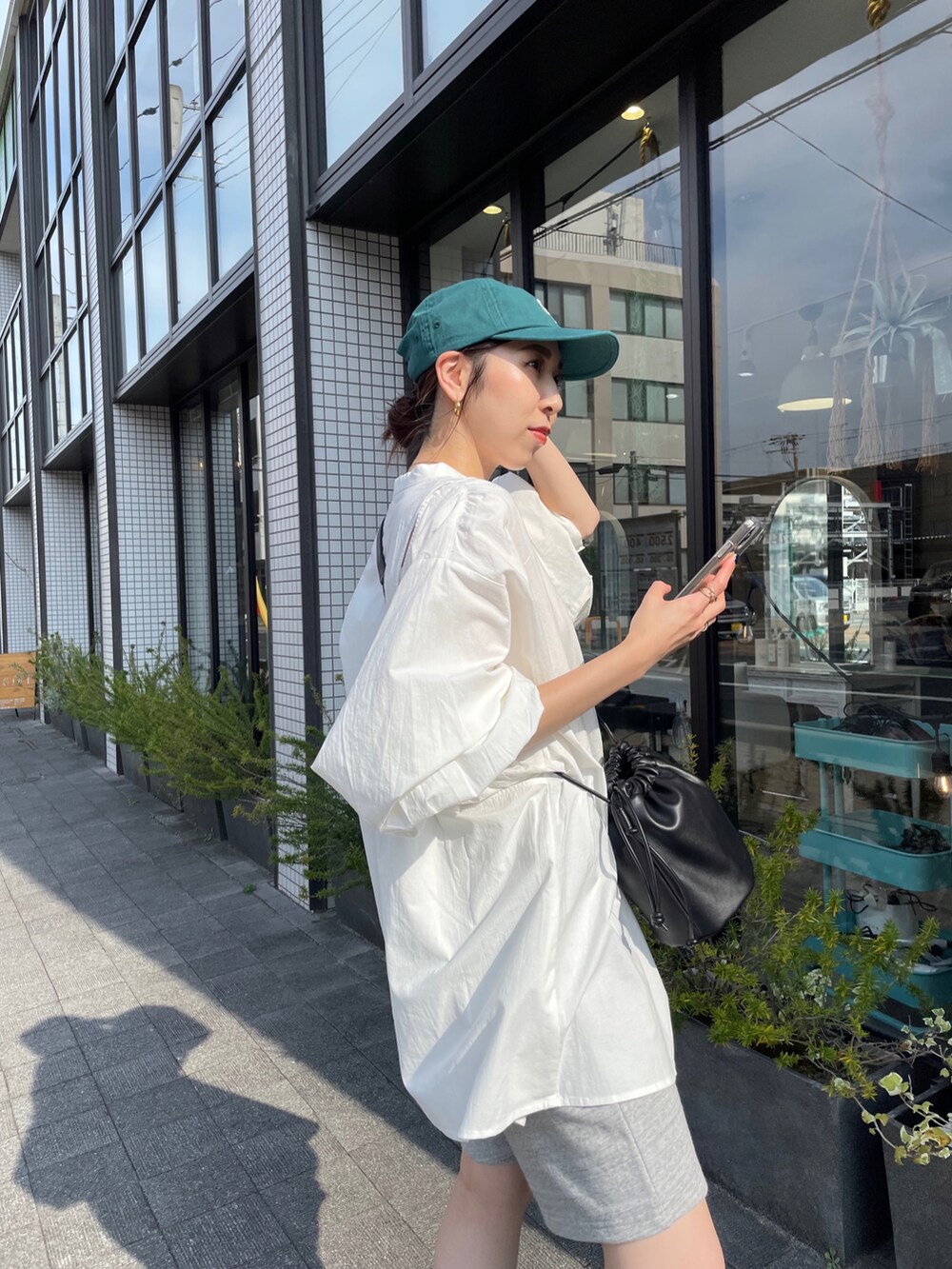 ホワイト系のシャツ/ブラウス、ブラック系のハンドバッグ、ブラック系のブーツを着用したレディースの夏コーディネートの4枚目の写真