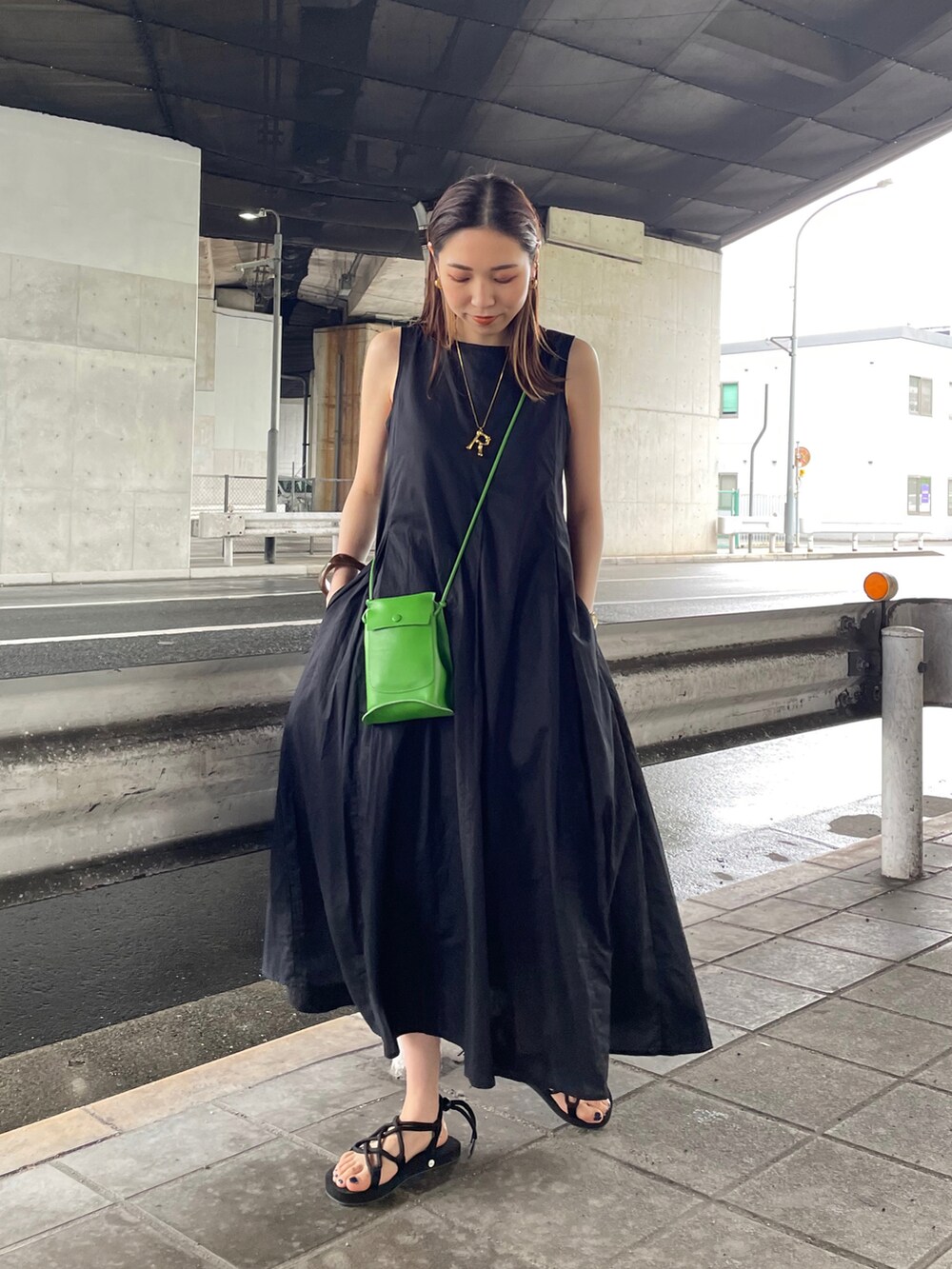 ブラック系のワンピース、ブラック系のサンダル、グリーン系のショルダーバッグを着用したレディースの春コーディネートの3枚目の写真