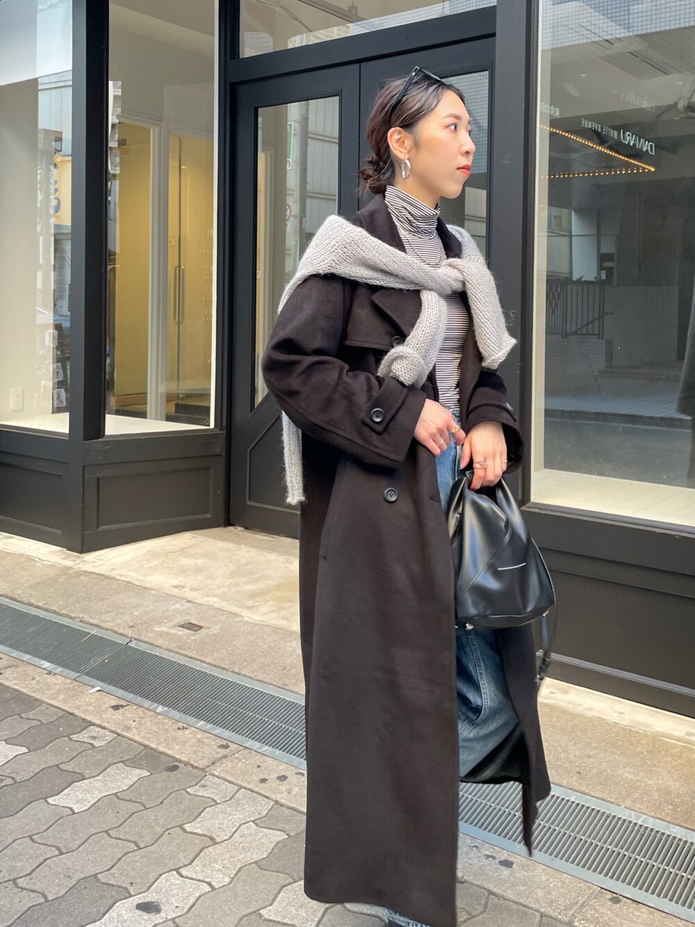 ブルー系のデニムパンツ、ブラック系のブーツ、ブラック系のチェスターコートを着用したレディースの秋コーディネートの4枚目の写真