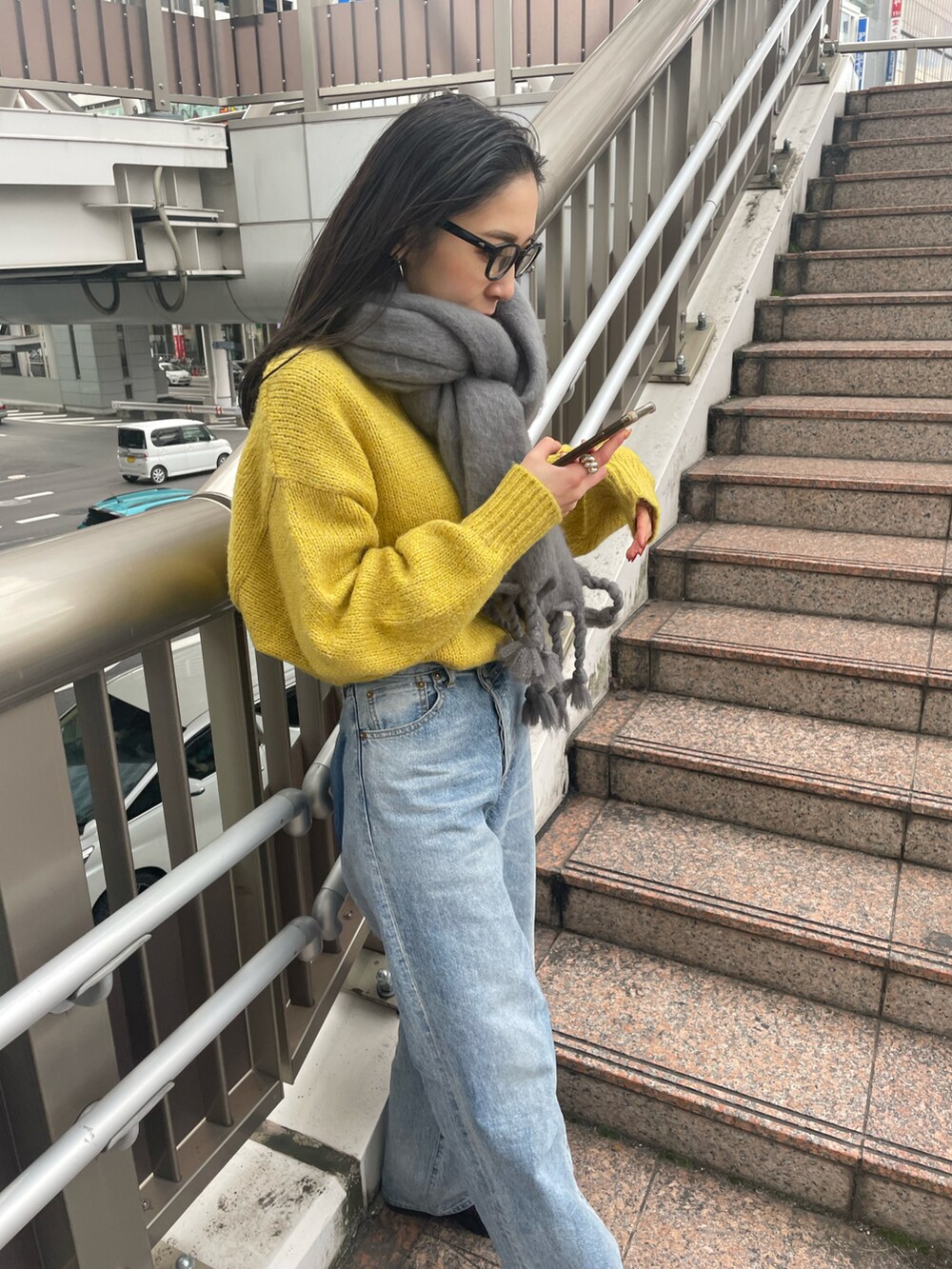 ブルー系のデニムパンツ、ブラック系のブーツ、イエロー系のニット/セーターを着用したレディースの冬コーディネートの4枚目の写真