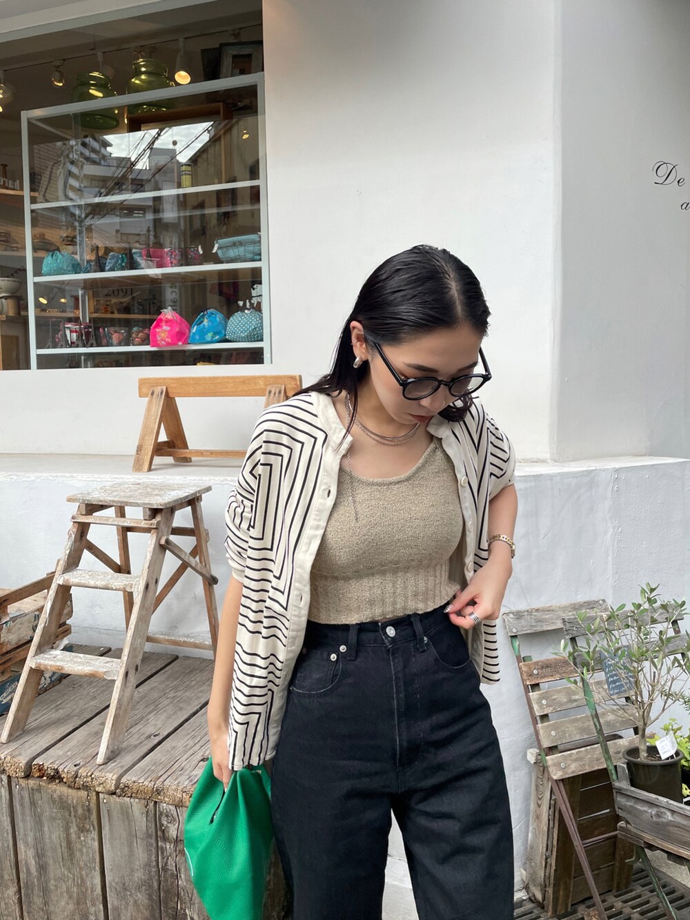 ブラック系のデニムパンツ、グリーン系のショルダーバッグ、ゴールド系のパンプスを着用したレディースの秋コーディネートの5枚目の写真