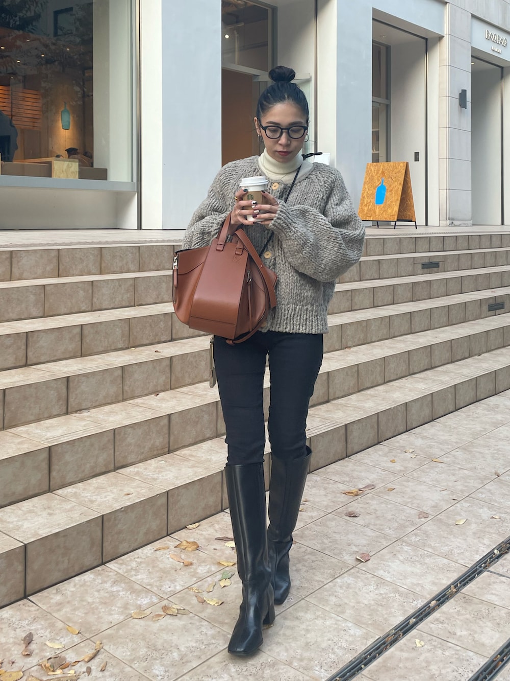 ブラウン系のバックパック/リュック、ブラック系のデニムパンツ、ブラック系のブーツを着用したレディースの秋コーディネートの2枚目の写真