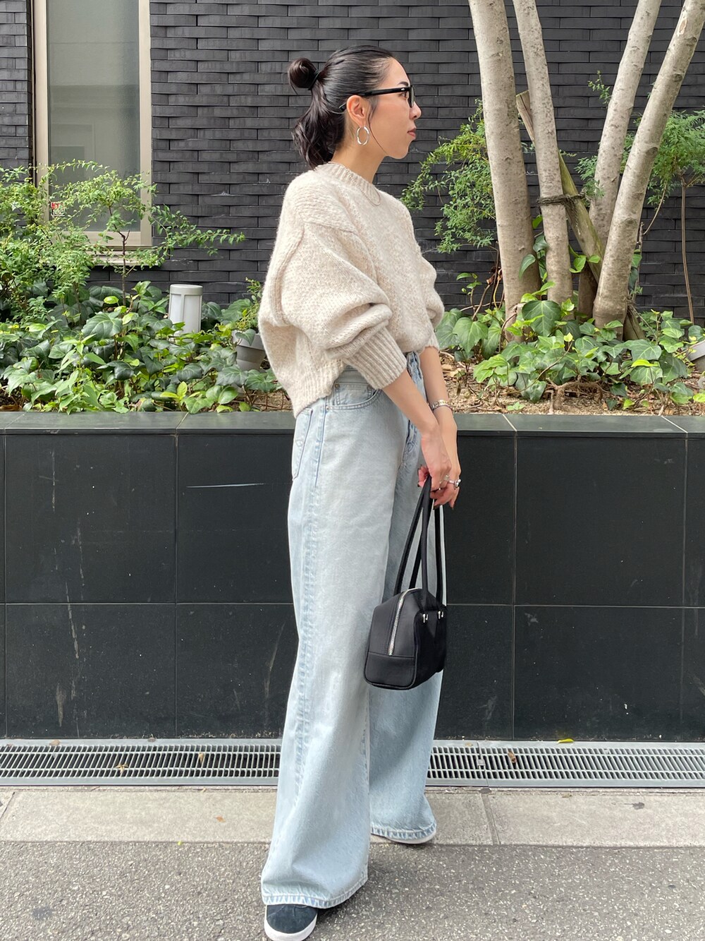 ブルー系のデニムパンツ、ホワイト系のニット/セーター、ブラック系のスニーカーを着用したレディースの秋コーディネートの2枚目の写真