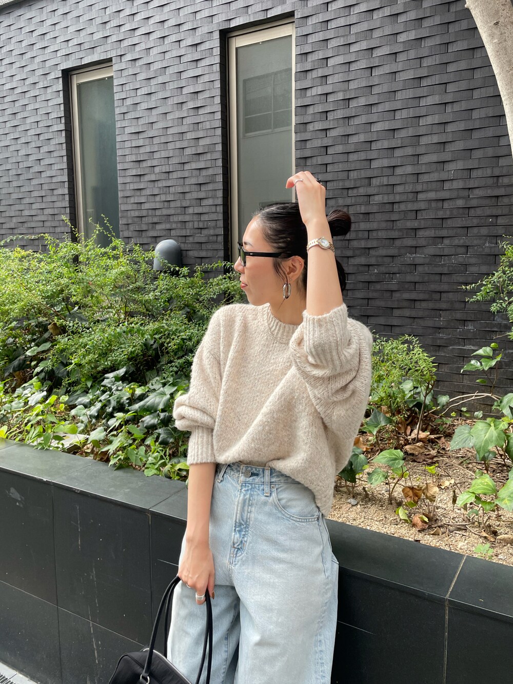 ブルー系のデニムパンツ、ホワイト系のニット/セーター、ブラック系のスニーカーを着用したレディースの秋コーディネートの3枚目の写真