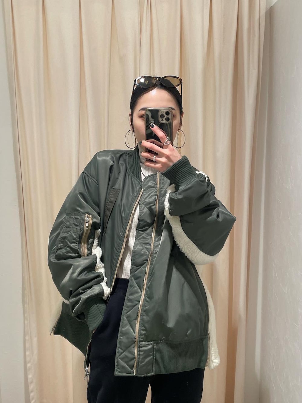 グリーン系のMA-1、ホワイト系のニット/セーター、ブラック系のスウェットパンツを着用したレディースの冬コーディネートの2枚目の写真