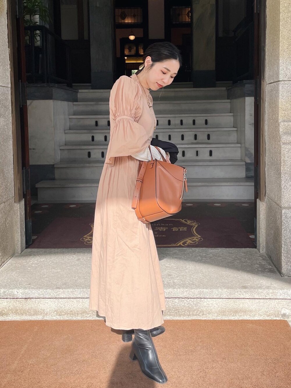 ベージュ系のワンピース、ブラウン系のハンドバッグを着用したレディースの春コーディネートの3枚目の写真