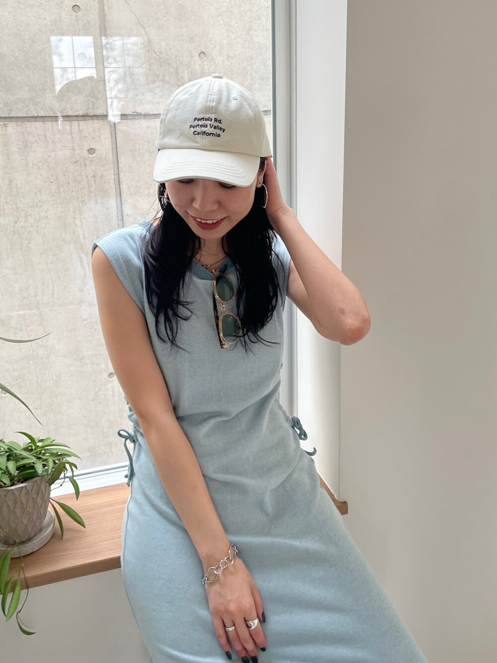 ブルー系のワンピース、ホワイト系のサンダル、ホワイト系のキャップを着用したレディースの春コーディネートの3枚目の写真