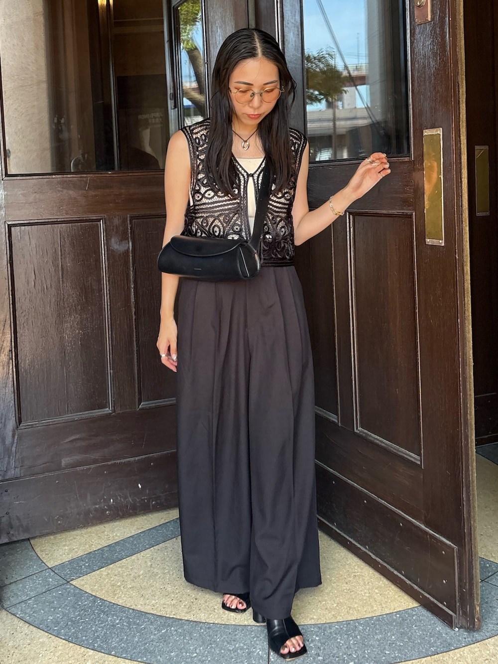 ブラック系のサンダル、ブラック系のスラックス、ブラック系のベストを着用したレディースの夏コーディネートの3枚目の写真