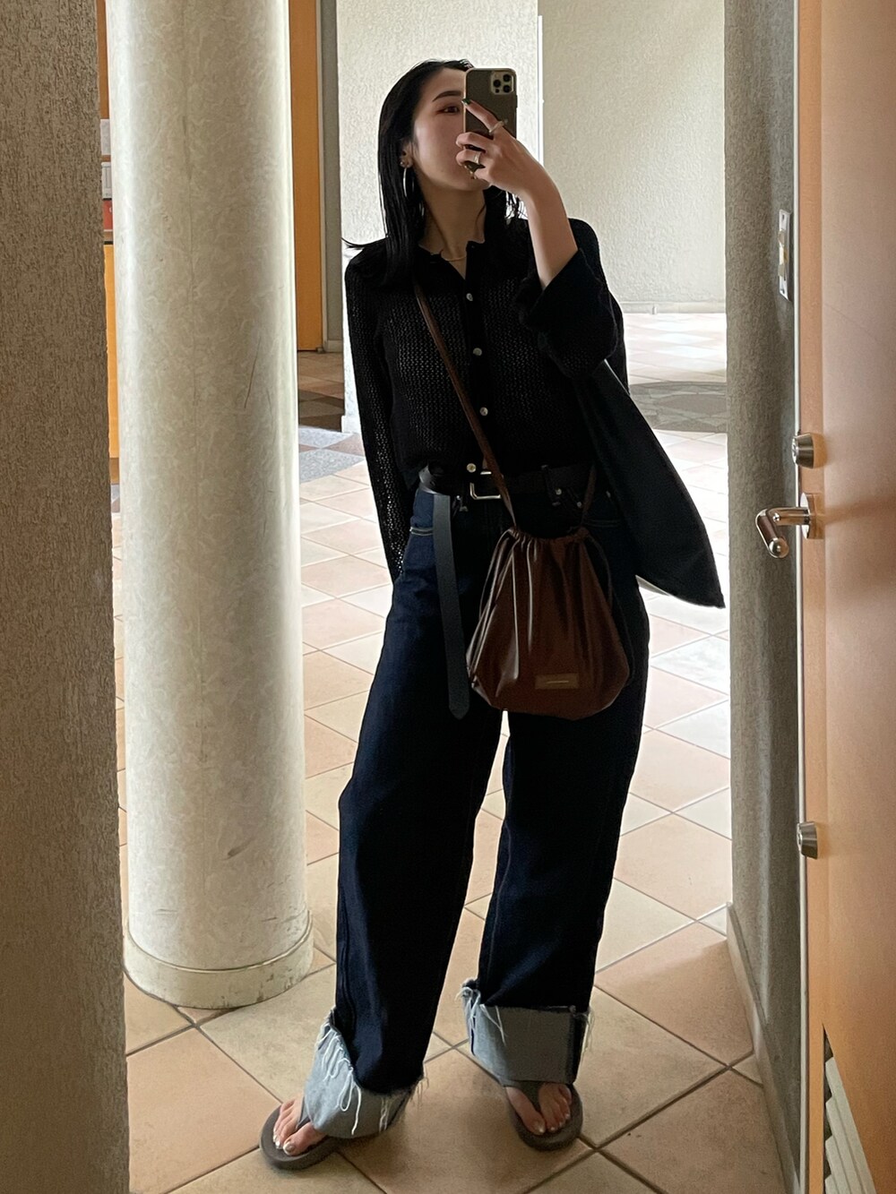 グレー系のサンダル、ブルー系のデニムパンツ、ブラック系のカーディガン/ボレロを着用したレディースの夏コーディネートの2枚目の写真