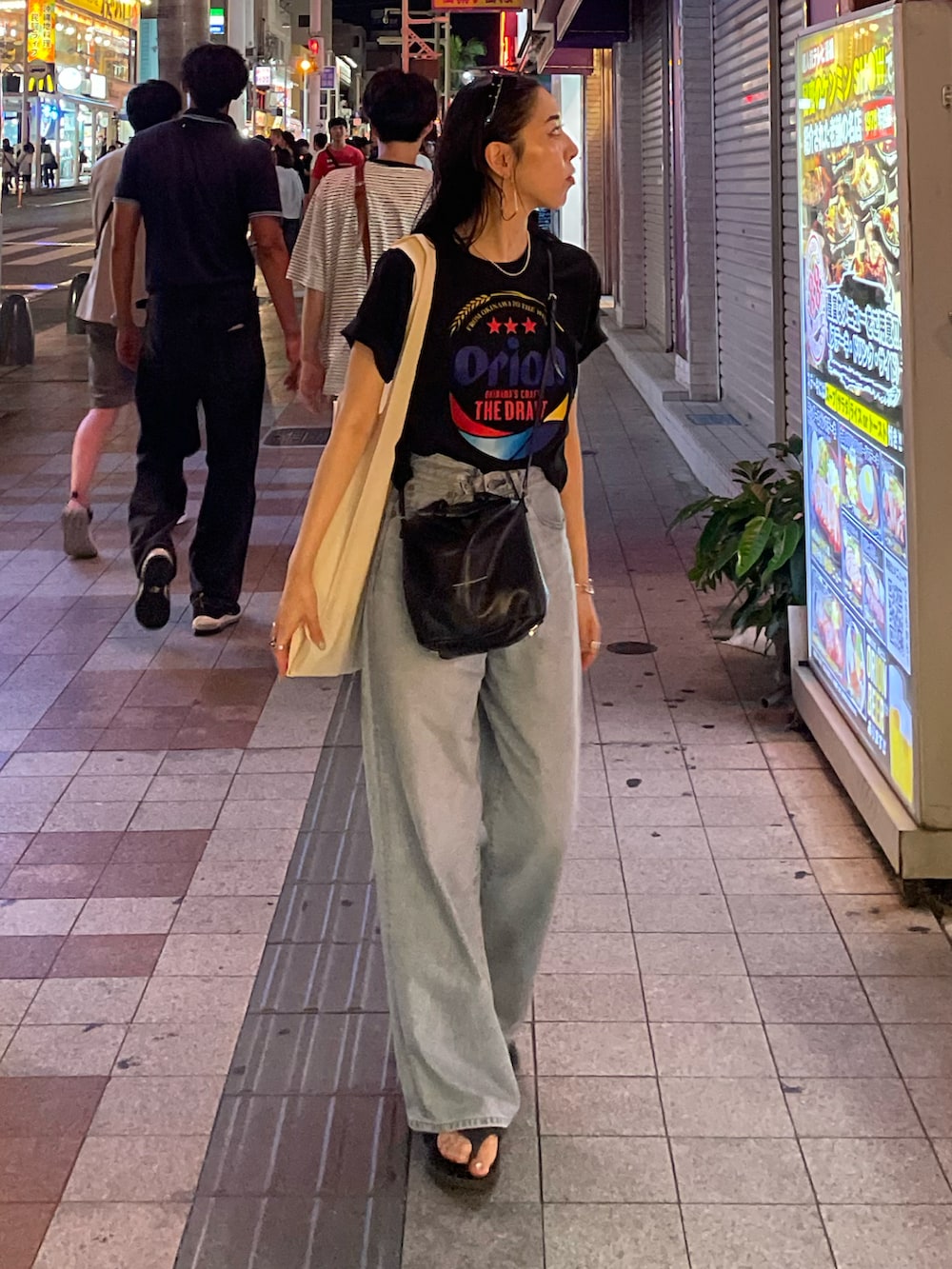 ブルー系のデニムパンツ、ブラック系のショルダーバッグ、ブラック系のサンダルを着用したレディースの秋コーディネートの2枚目の写真