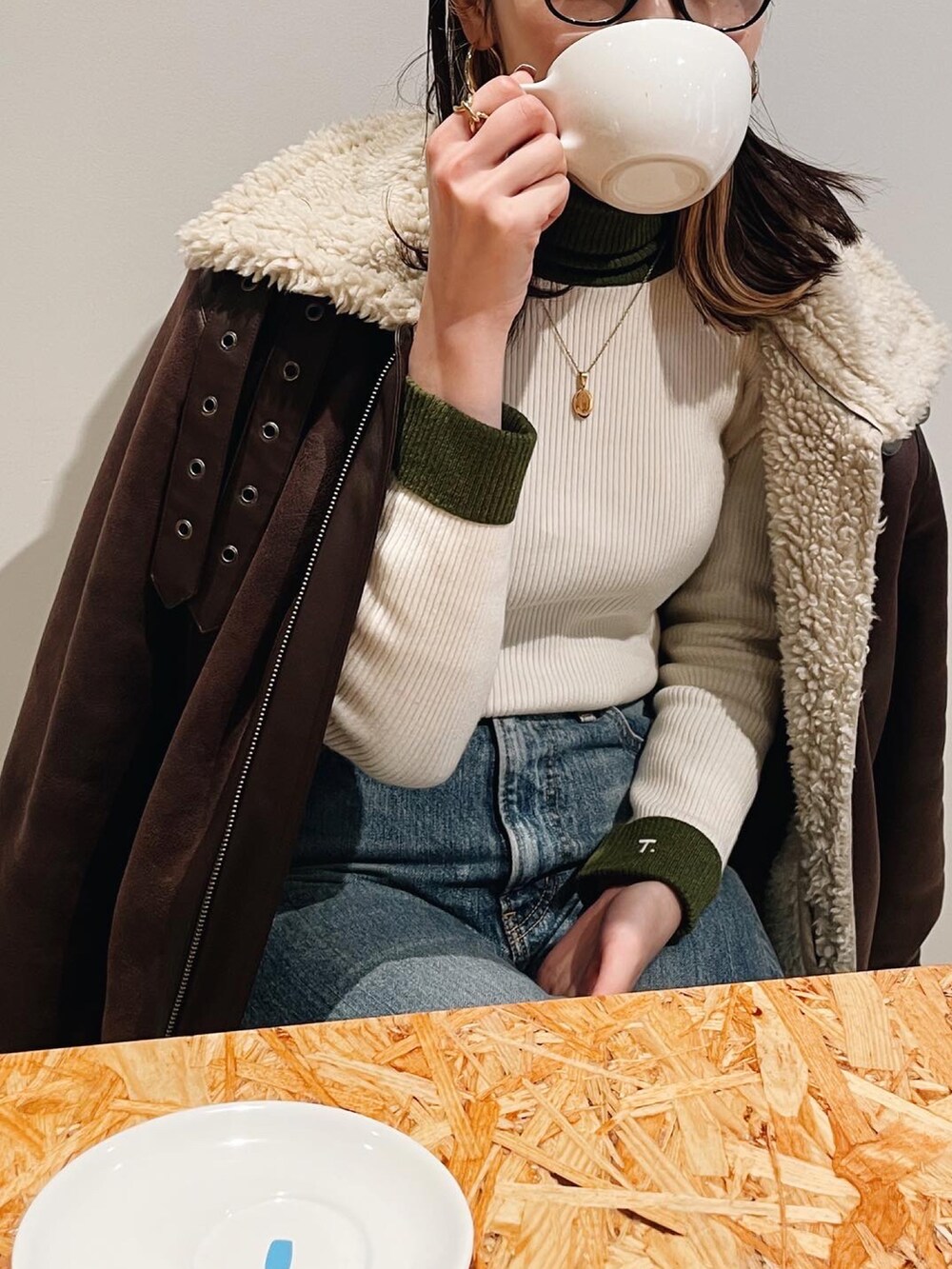 ブルー系のデニムパンツ、ブラウン系のブルゾン、ホワイト系のニット/セーターを着用したレディースの冬コーディネートの2枚目の写真