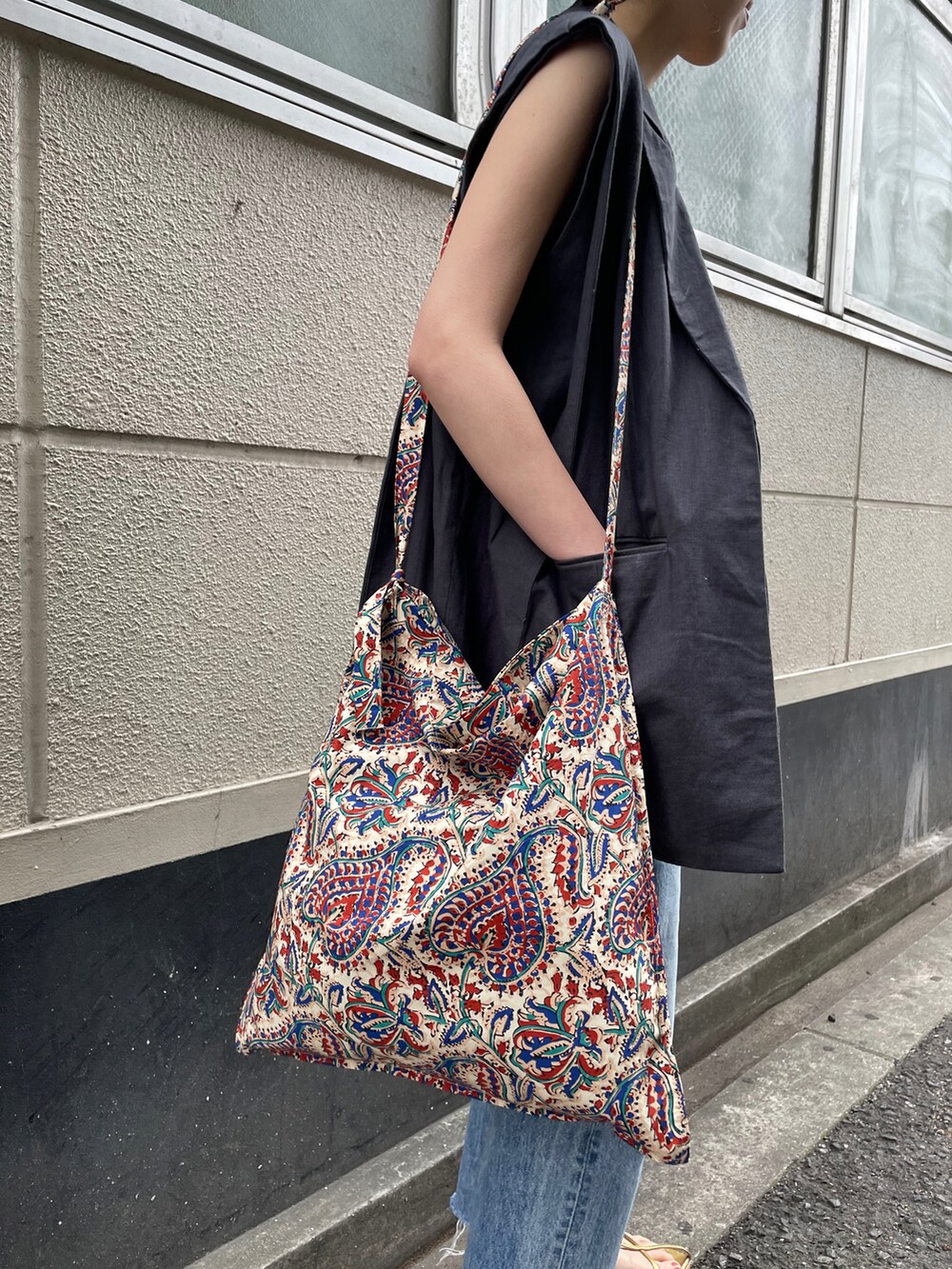 ブルー系のデニムパンツ、ゴールド系のサンダル、ホワイト系のショルダーバッグを着用したレディースの春コーディネートの5枚目の写真