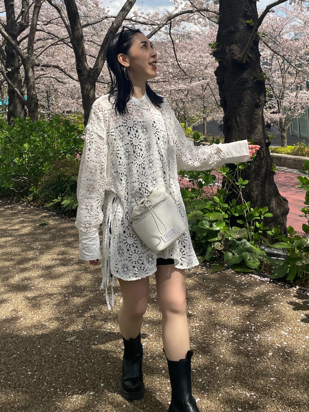 ブラック系のブーツ、ホワイト系のシャツ/ブラウス、ホワイト系のショルダーバッグを着用したレディースの春コーディネートの2枚目の写真