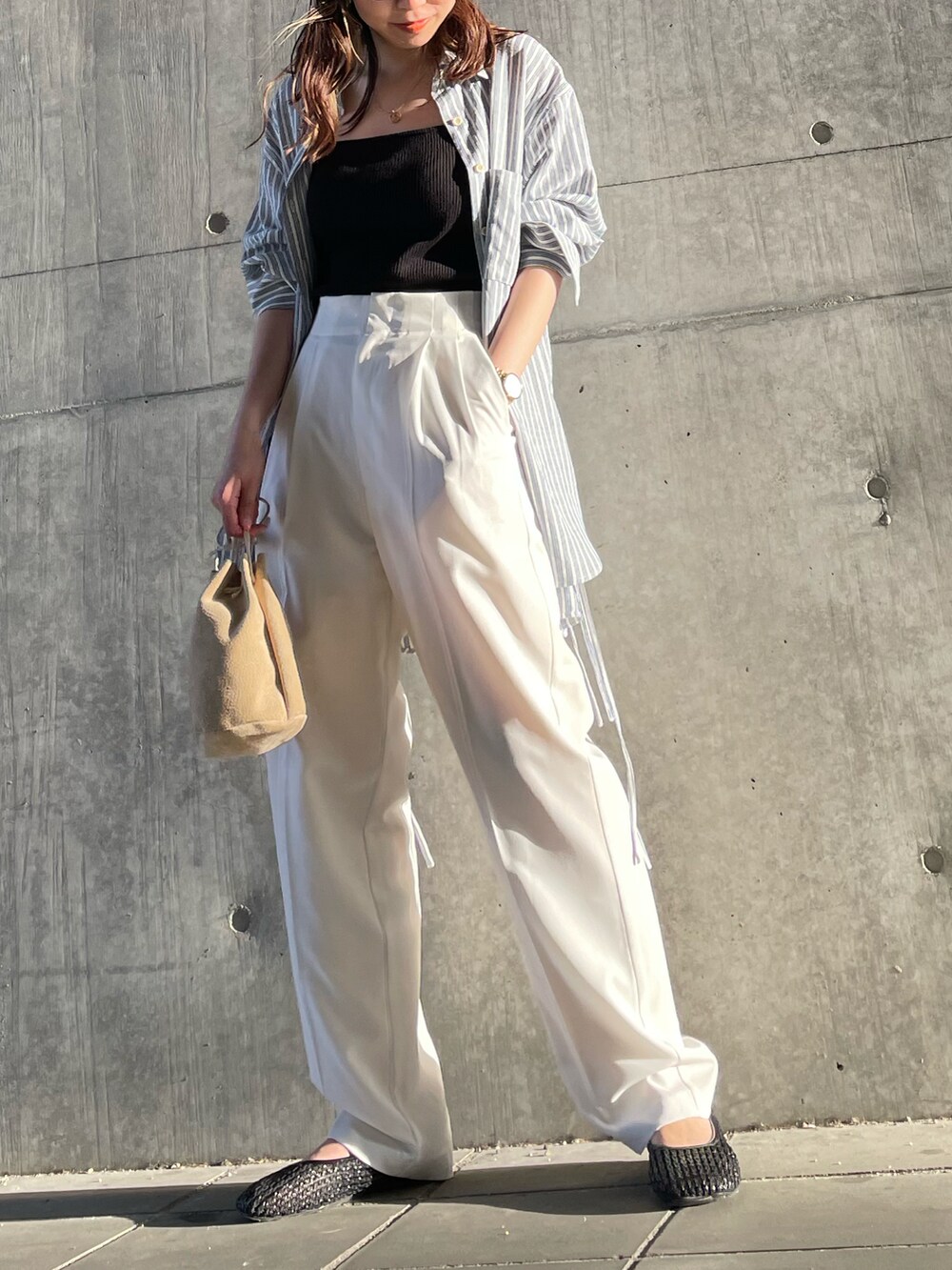 ブラック系のキャミソール、ブルー系のシャツ/ブラウス、ベージュ系のハンドバッグを着用したレディースの春コーディネートの2枚目の写真