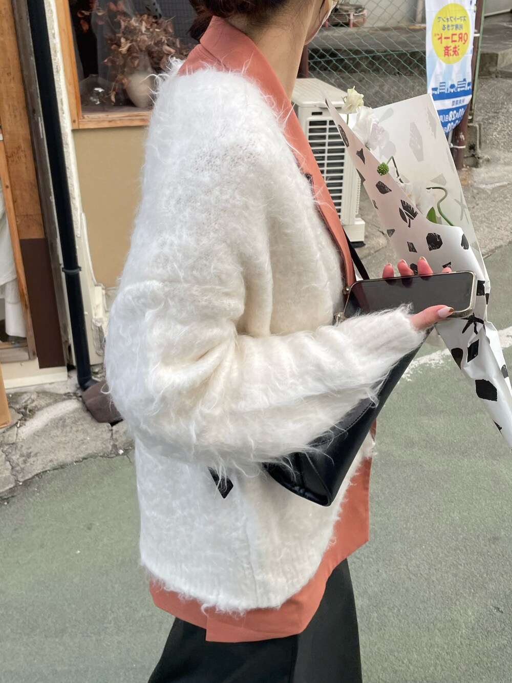 ブラック系のショルダーバッグ、ブラック系のスカート、ホワイト系のカーディガン/ボレロを着用したレディースの冬コーディネートの4枚目の写真