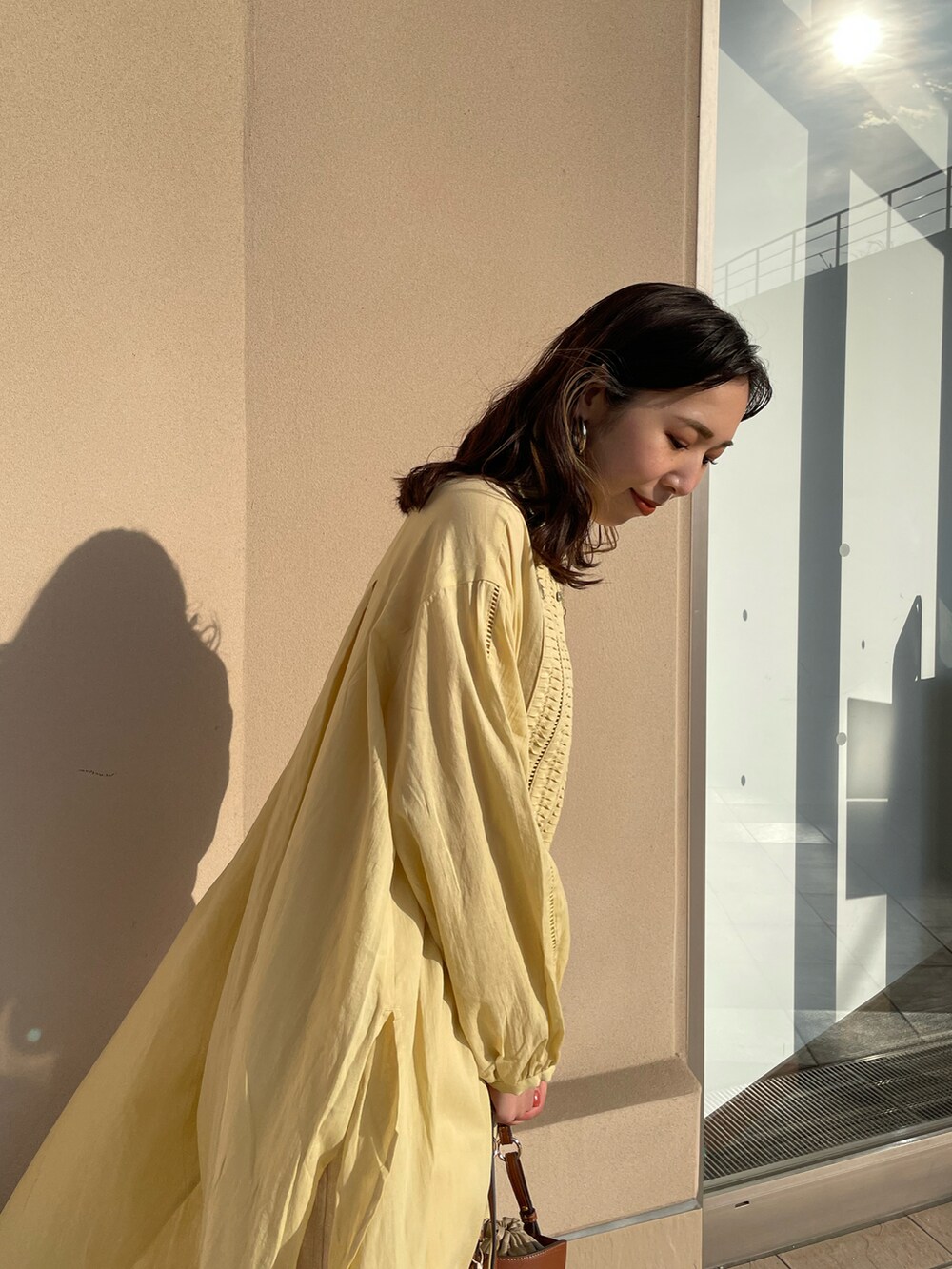 イエロー系のワンピース、ホワイト系のその他パンツ、ブラウン系のショルダーバッグを着用したレディースの春コーディネートの4枚目の写真