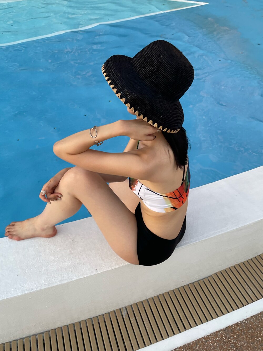ブラック系のハット、ブラック系の水着、ホワイト系の水着を着用したレディースの夏コーディネートの5枚目の写真