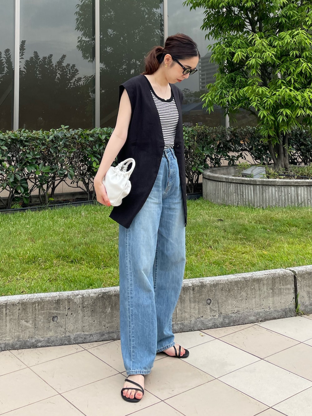 ホワイト系のタンクトップ、ブラック系のベスト、ブルー系のデニムパンツを着用したレディースの夏コーディネートの2枚目の写真
