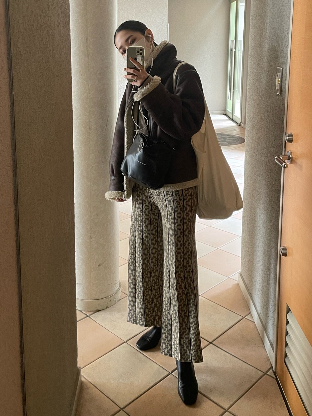 ベージュ系のその他パンツ、ブラウン系のムートンコート、ブラック系のショルダーバッグを着用したレディースの冬コーディネートの2枚目の写真