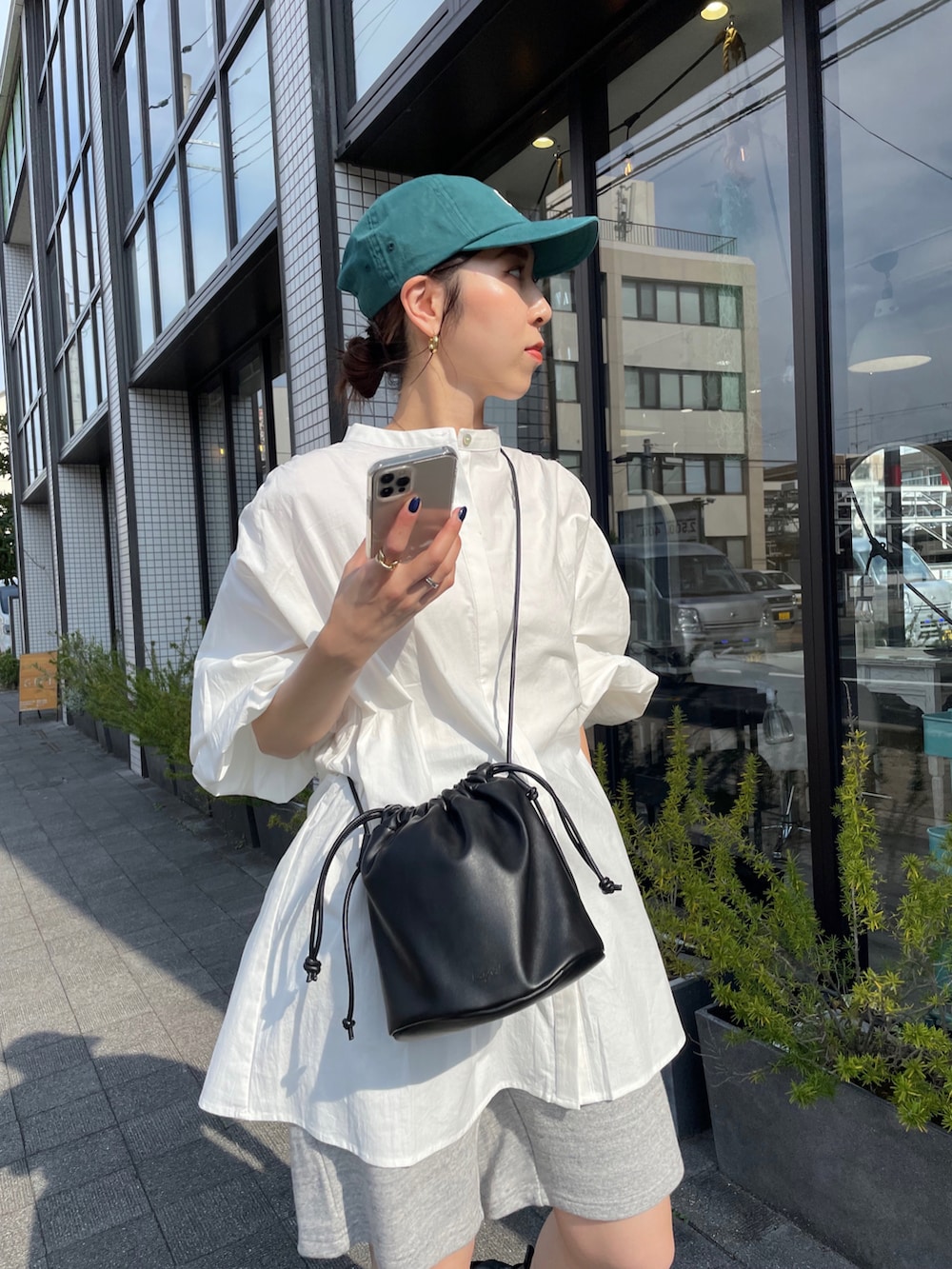 ホワイト系のシャツ/ブラウス、ブラック系のハンドバッグ、ブラック系のブーツを着用したレディースの夏コーディネートの5枚目の写真