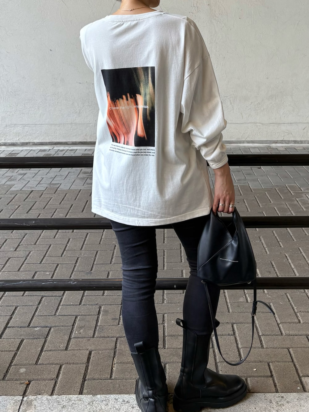 ブラック系のデニムパンツ、ブラック系のブーツ、ブラック系のショルダーバッグを着用したレディースの秋コーディネートの5枚目の写真