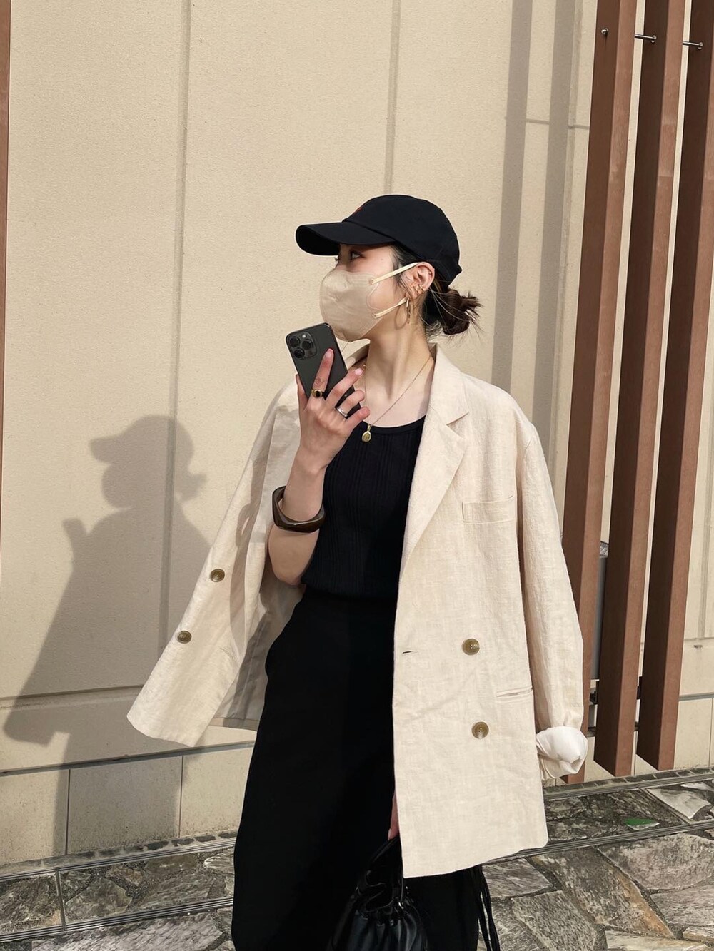 ブラック系のショルダーバッグ、ホワイト系のテーラードジャケット、ブラック系のスカートを着用したレディースの春コーディネートの5枚目の写真