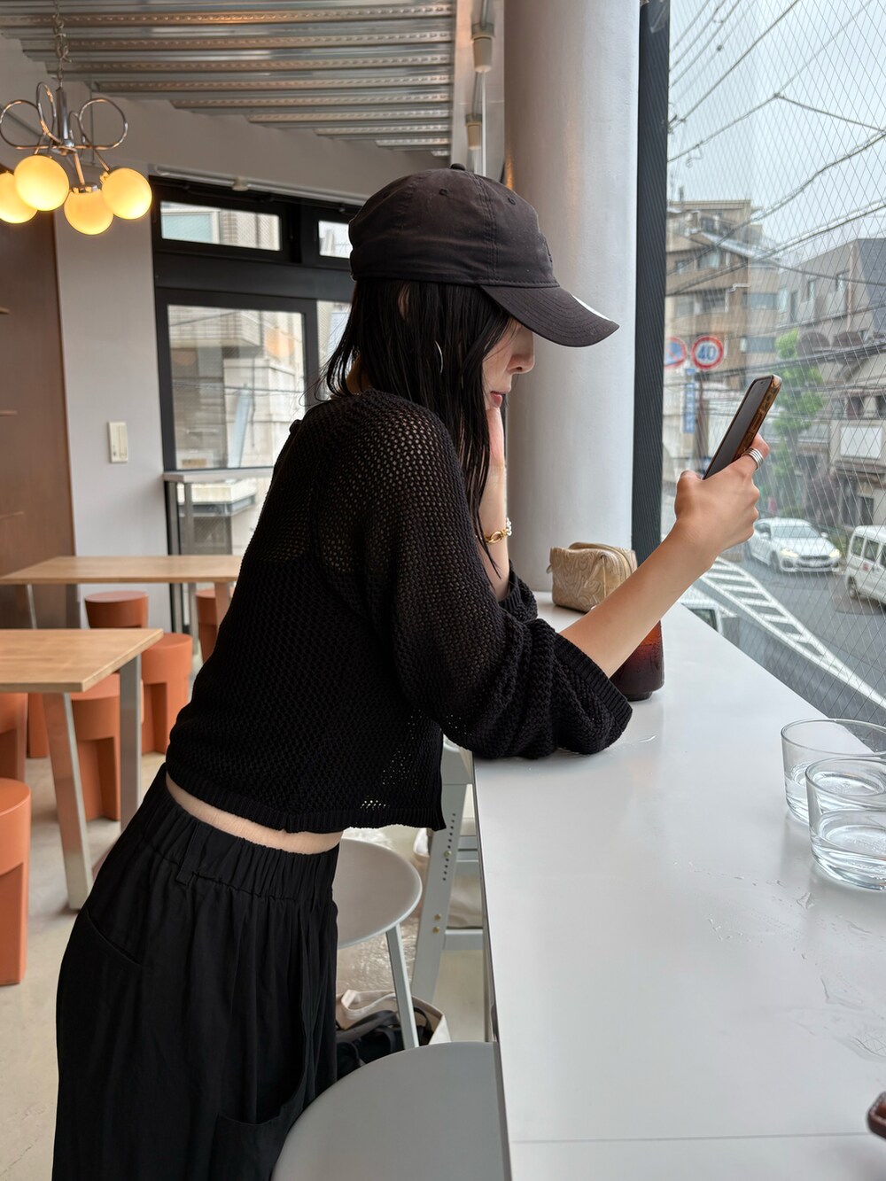 ホワイト系のスニーカー、ブラック系のカーディガン/ボレロ、ブラック系のキャップを着用したレディースの夏コーディネートの4枚目の写真