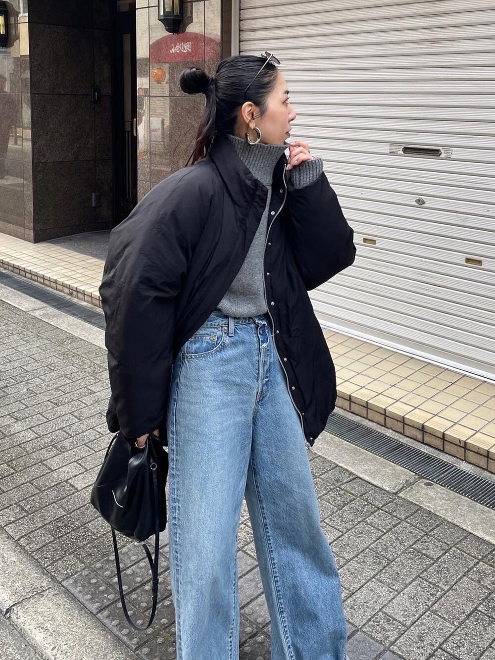 グレー系のニット/セーター、ブラック系のブルゾン、ブルー系のデニムパンツを着用したレディースの冬コーディネートの2枚目の写真