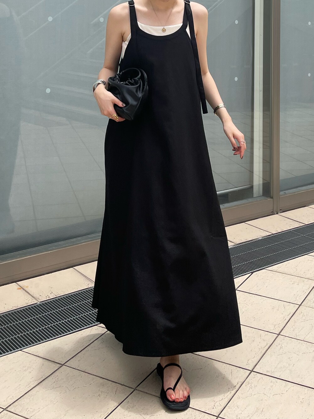 ブラック系のハンドバッグ、ブラック系のワンピース、ブラック系のサンダルを着用したレディースの夏コーディネートの4枚目の写真