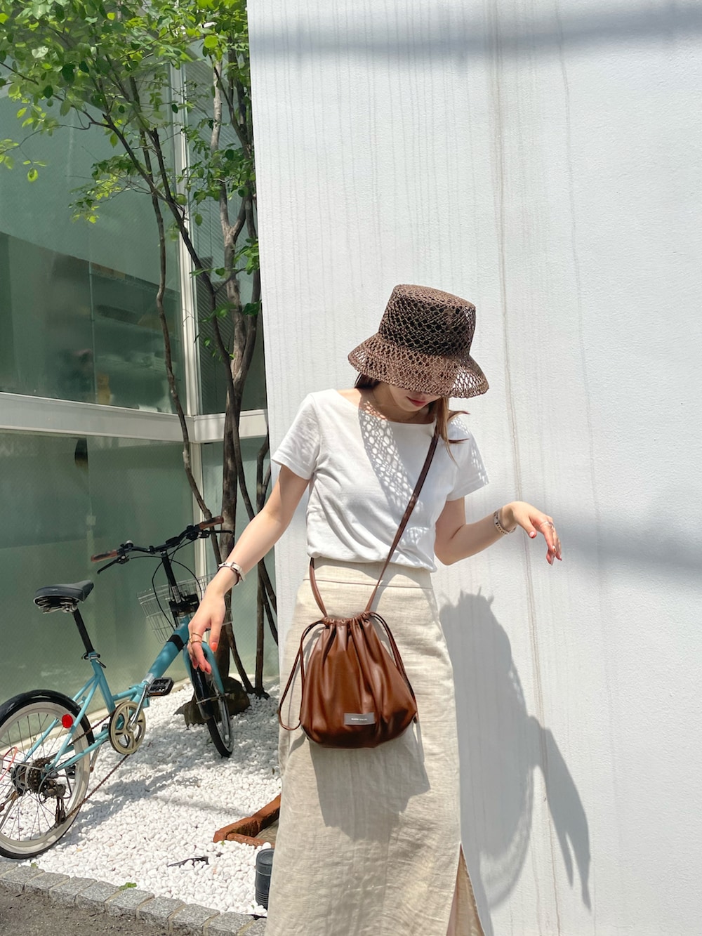 ホワイト系のTシャツ/カットソー、ブラウン系のショルダーバッグ、ブラウン系のサンダルを着用したレディースの夏コーディネートの2枚目の写真