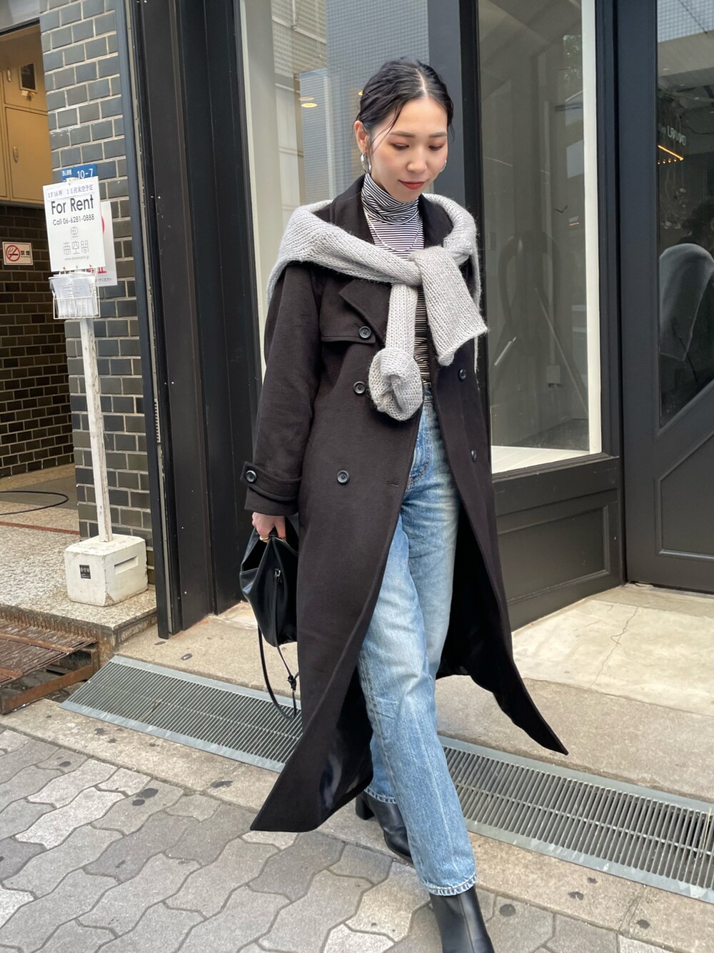 ブルー系のデニムパンツ、ブラック系のブーツ、ブラック系のチェスターコートを着用したレディースの秋コーディネートの2枚目の写真