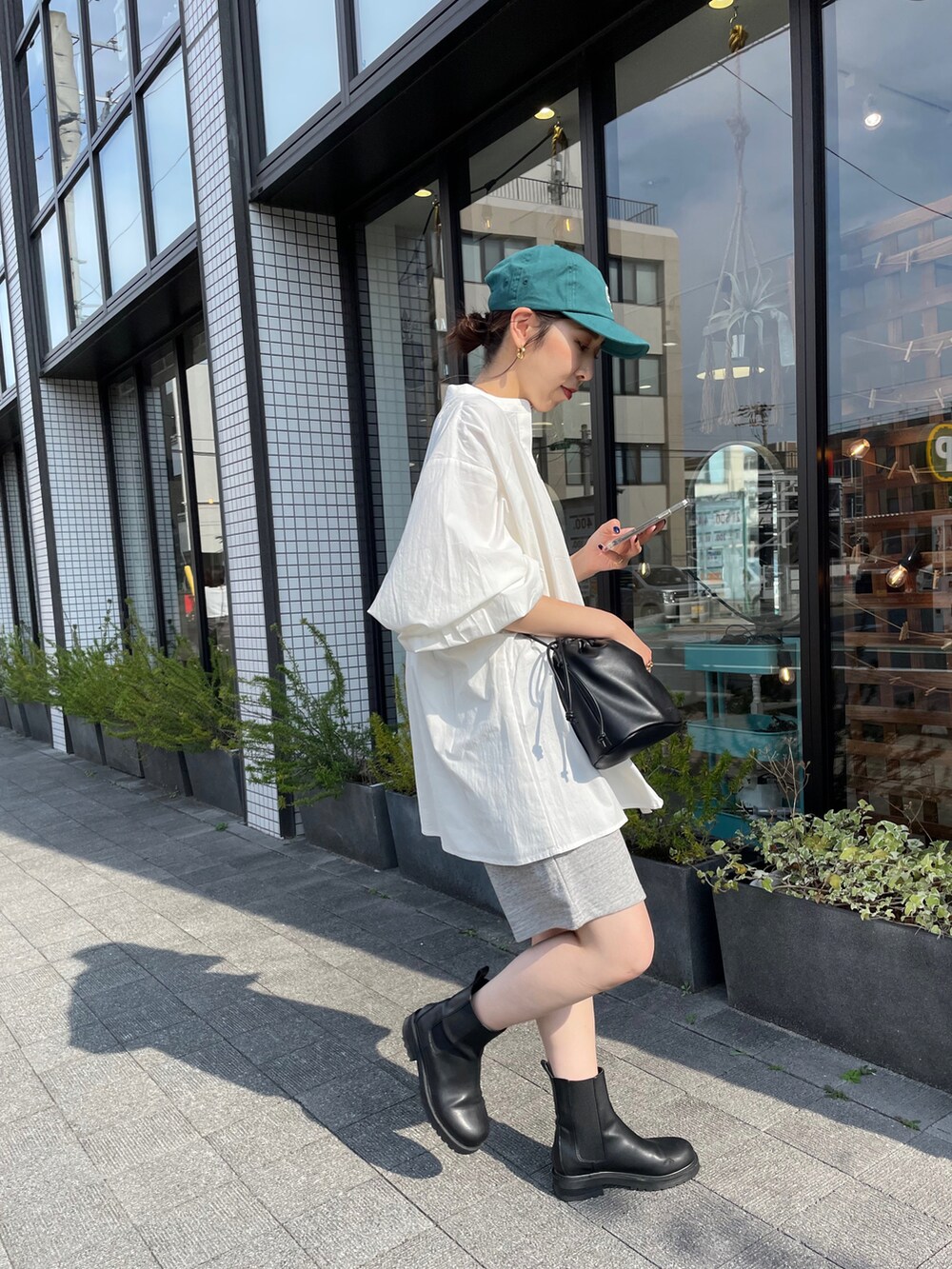 ホワイト系のシャツ/ブラウス、ブラック系のハンドバッグ、ブラック系のブーツを着用したレディースの夏コーディネートの2枚目の写真