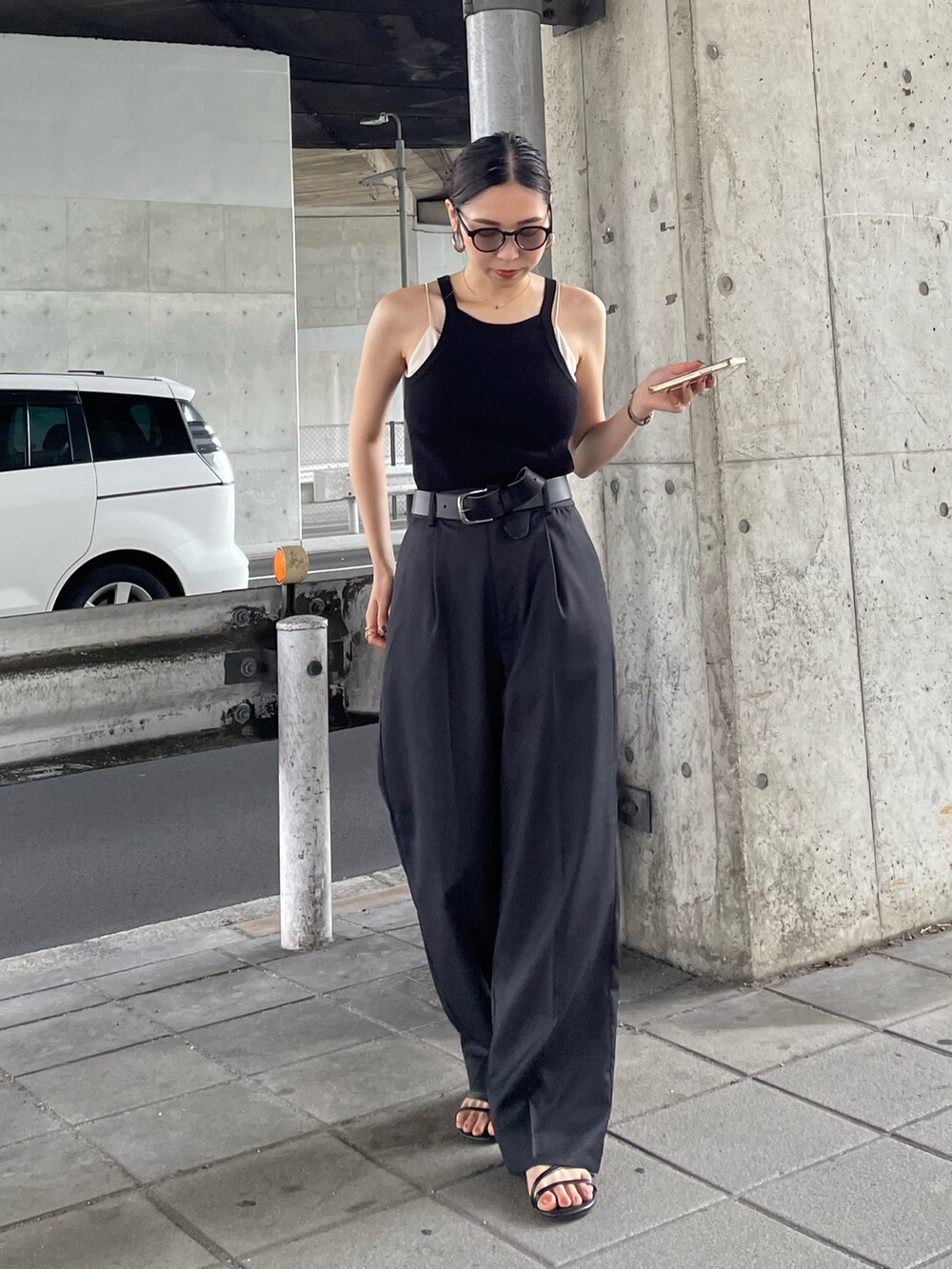 グレー系のスラックス、ブラック系のタンクトップ、ブラック系のベルトを着用したレディースの夏コーディネートの2枚目の写真