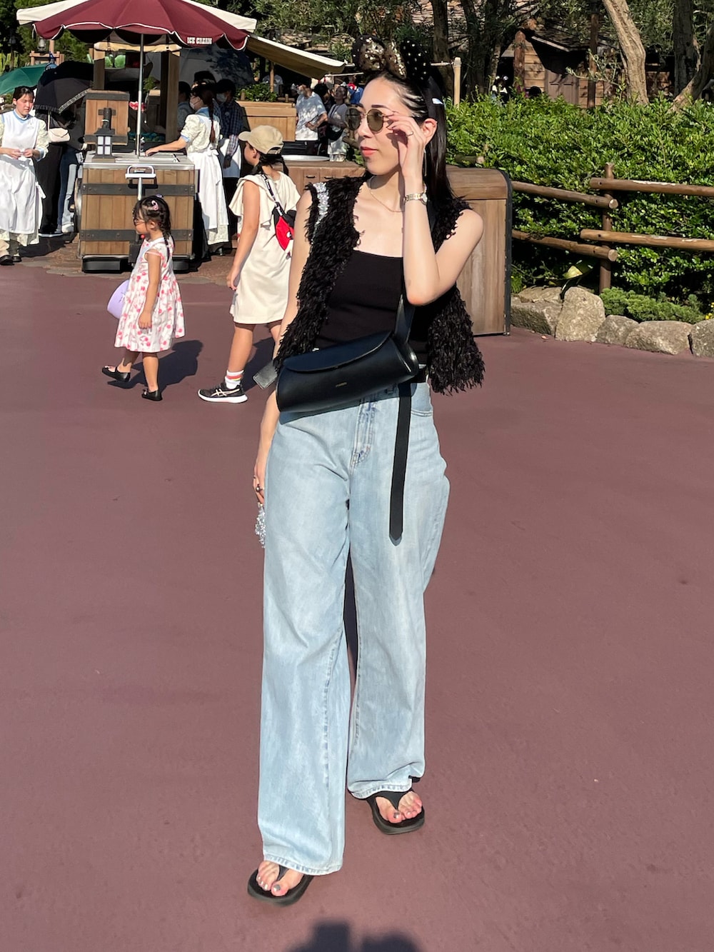 ブルー系のデニムパンツ、ブラック系のサンダル、ブラック系のキャミソールを着用したレディースの夏コーディネートの2枚目の写真