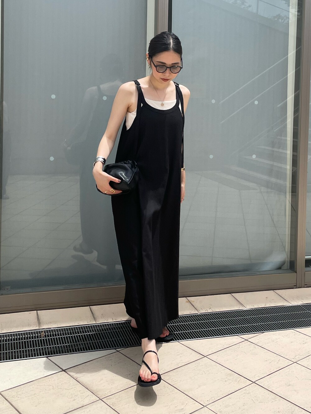 ブラック系のハンドバッグ、ブラック系のワンピース、ブラック系のサンダルを着用したレディースの夏コーディネートの2枚目の写真