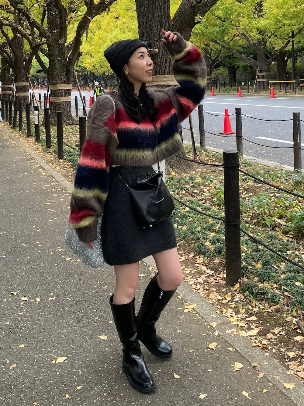 グレー系のスカート、ブラウン系のTシャツ/カットソー、ブラック系のショルダーバッグを着用したレディースの秋コーディネートの2枚目の写真