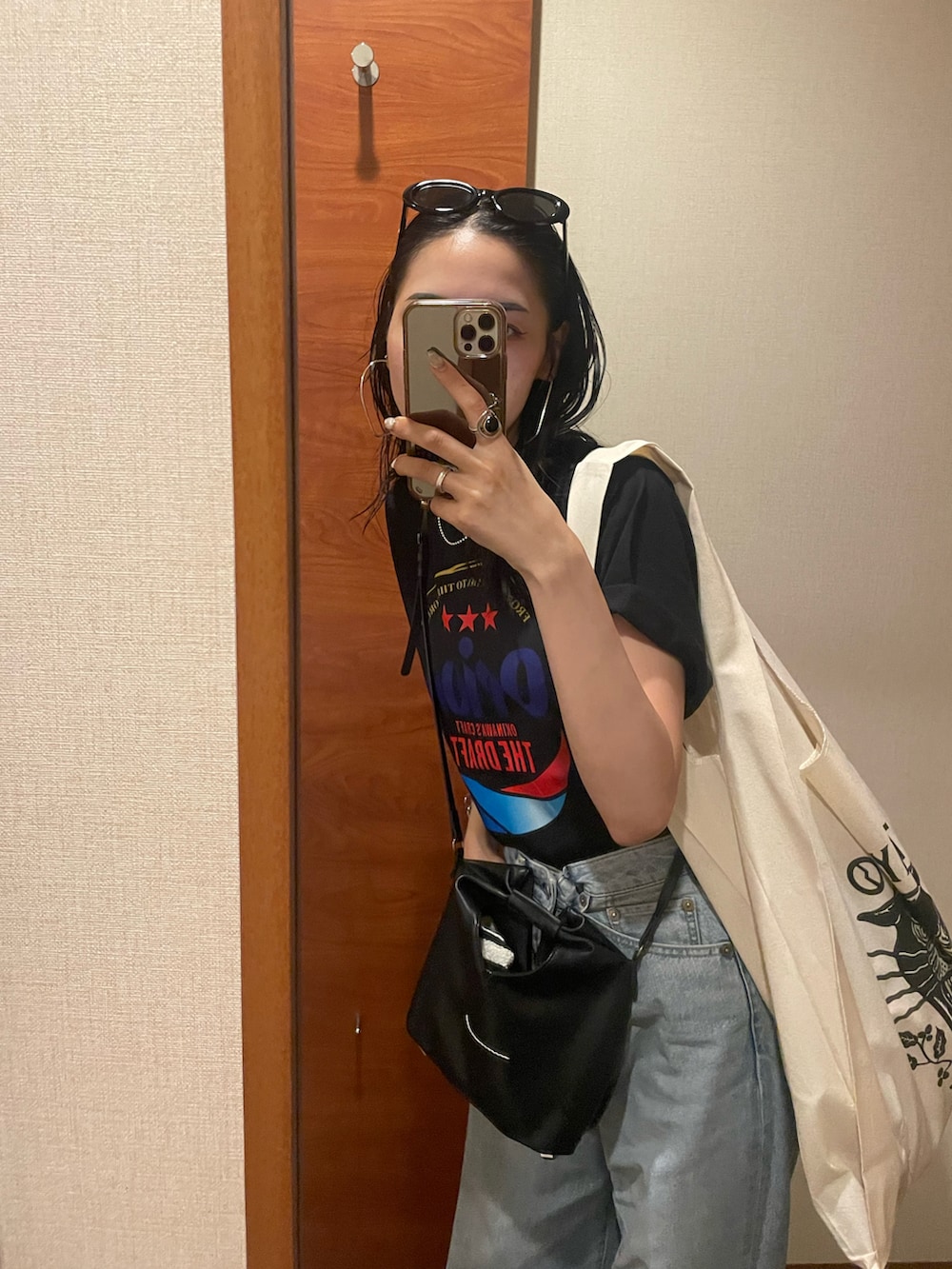 ブルー系のデニムパンツ、ブラック系のショルダーバッグ、ブラック系のサンダルを着用したレディースの秋コーディネートの5枚目の写真