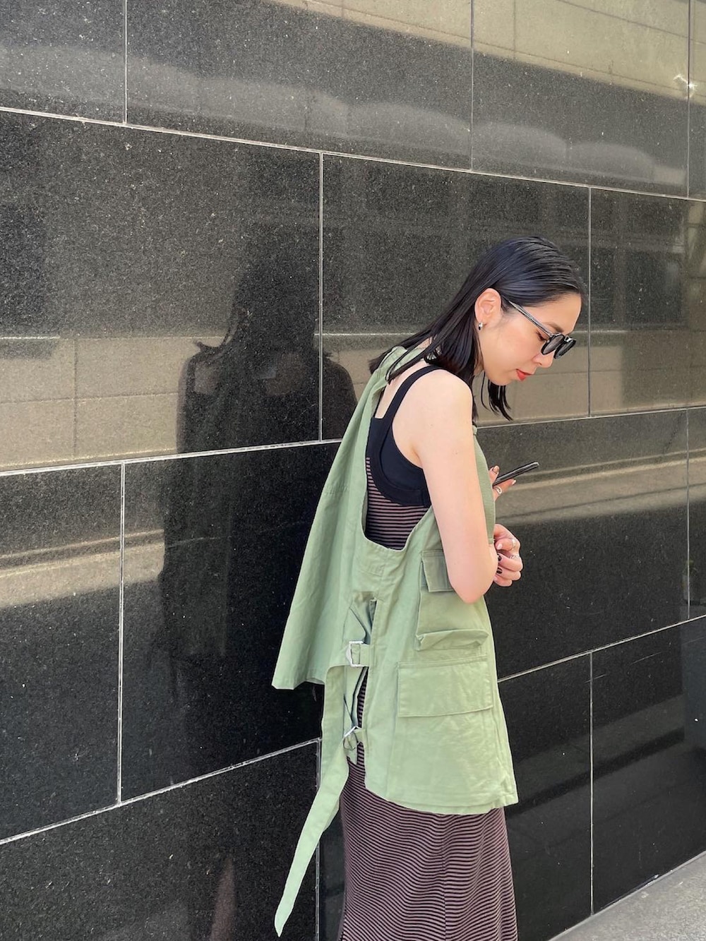 ブラック系のパンプス、ブラウン系のワンピース、グリーン系のベストを着用したレディースの春コーディネートの4枚目の写真