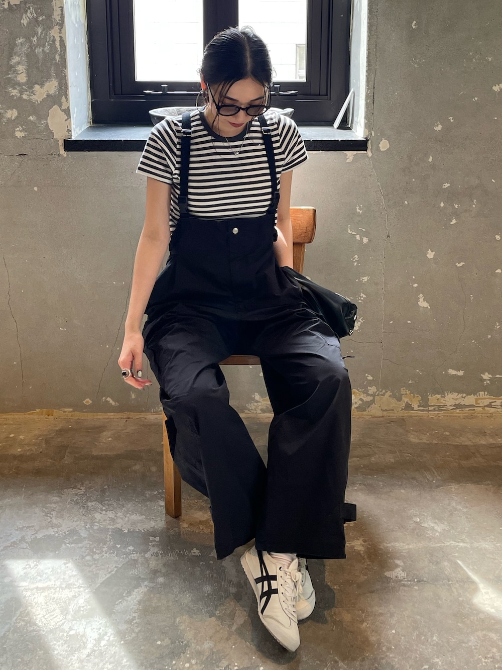 ブラック系のサロペット/オーバーオール、グレー系のTシャツ/カットソー、ホワイト系のスニーカーを着用したレディースの春コーディネートの2枚目の写真