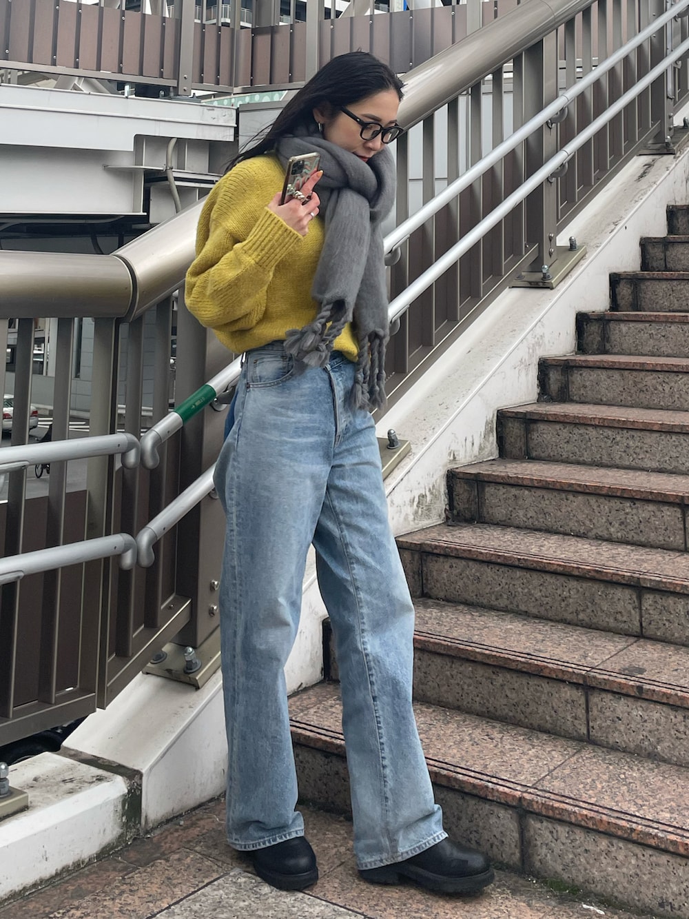 ブルー系のデニムパンツ、ブラック系のブーツ、イエロー系のニット/セーターを着用したレディースの冬コーディネートの2枚目の写真