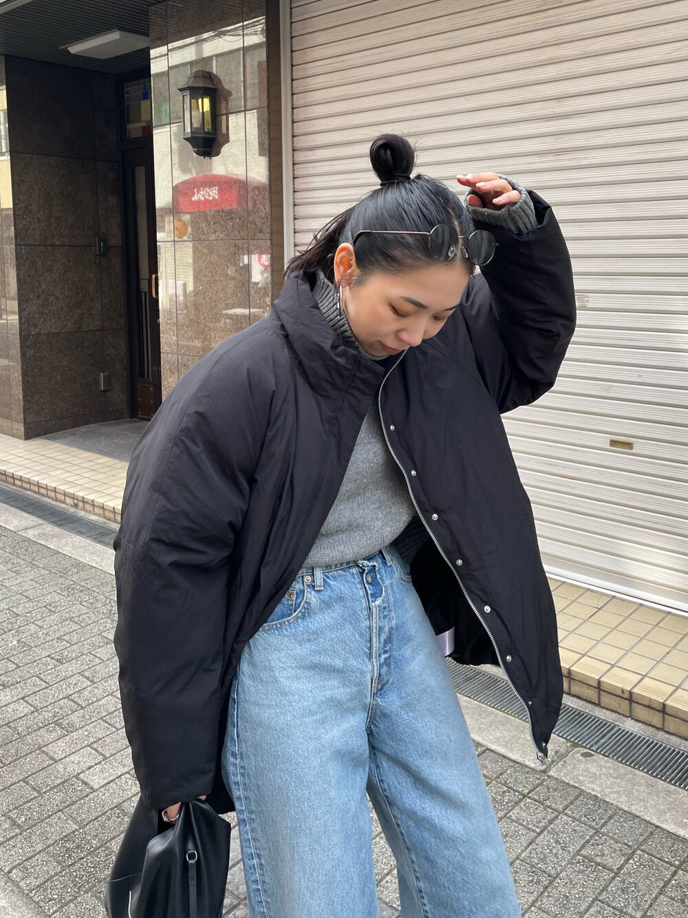 グレー系のニット/セーター、ブラック系のブルゾン、ブルー系のデニムパンツを着用したレディースの冬コーディネートの5枚目の写真