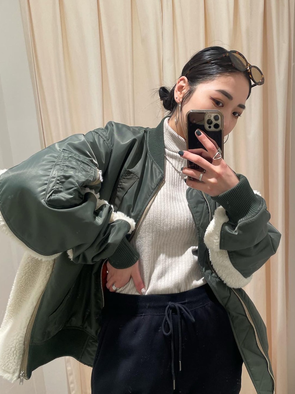 グリーン系のMA-1、ホワイト系のニット/セーター、ブラック系のスウェットパンツを着用したレディースの冬コーディネートの4枚目の写真