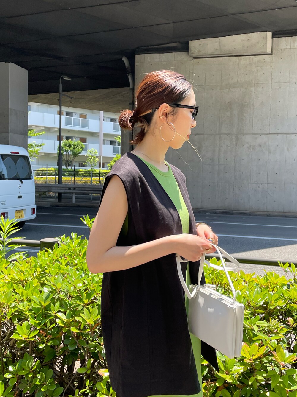 グリーン系のワンピース、ブラック系のベスト、ブラック系のスニーカーを着用したレディースの夏コーディネートの4枚目の写真