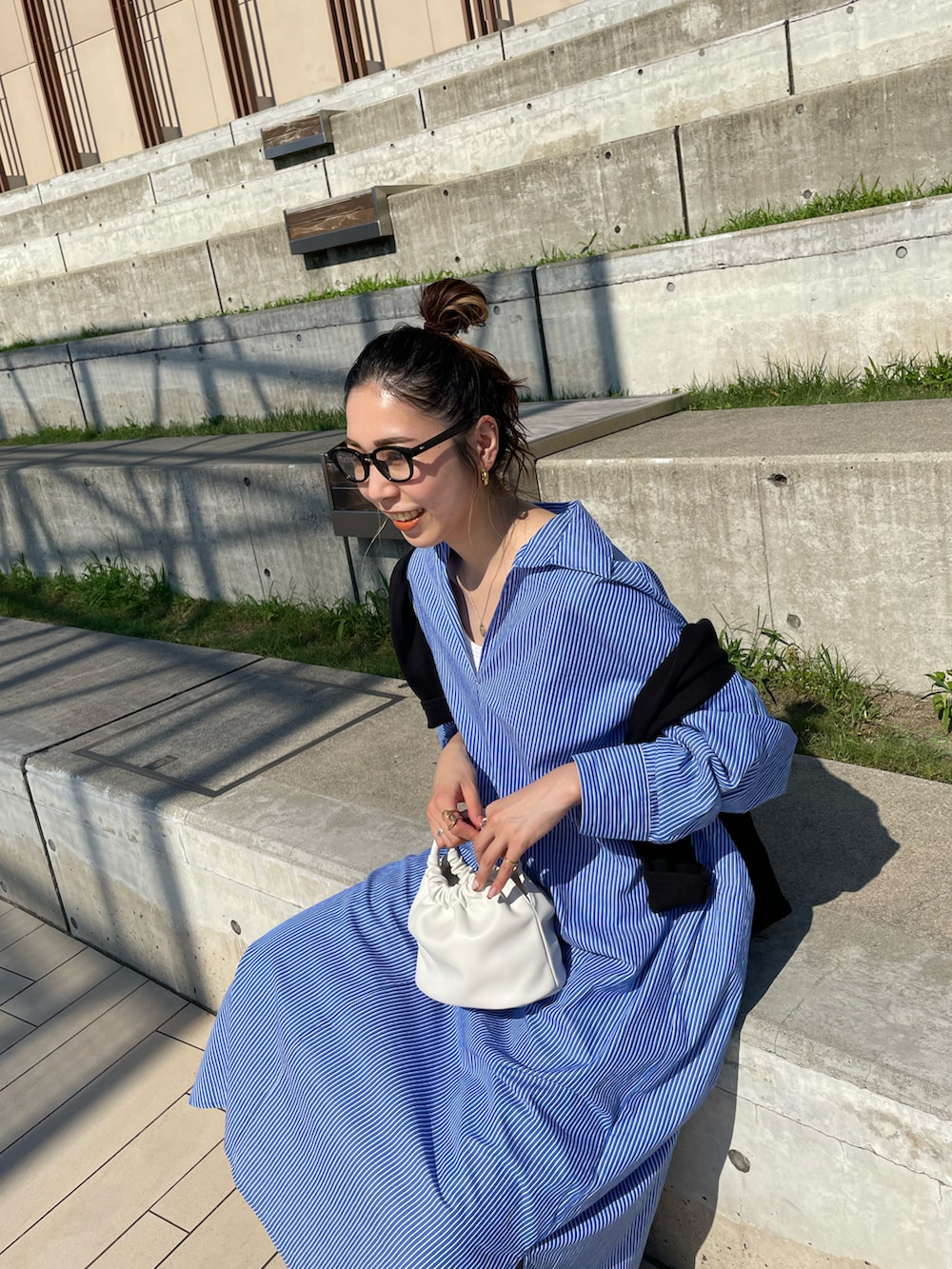 ブルー系のワンピース、ホワイト系のハンドバッグ、ブラック系のサンダルを着用したレディースの夏コーディネートの5枚目の写真