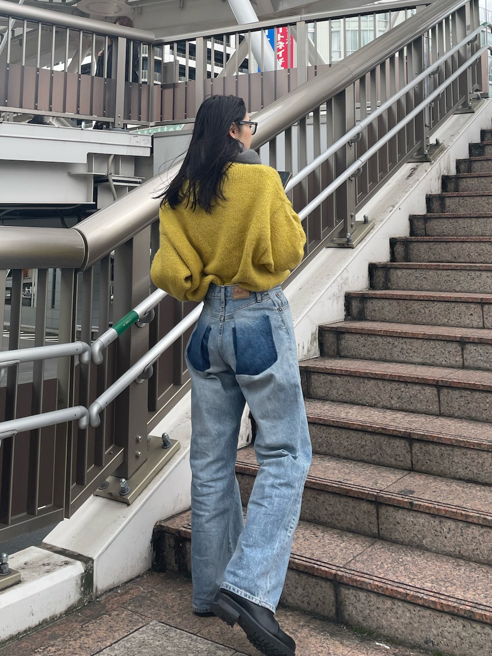 ブルー系のデニムパンツ、ブラック系のブーツ、イエロー系のニット/セーターを着用したレディースの冬コーディネートの3枚目の写真