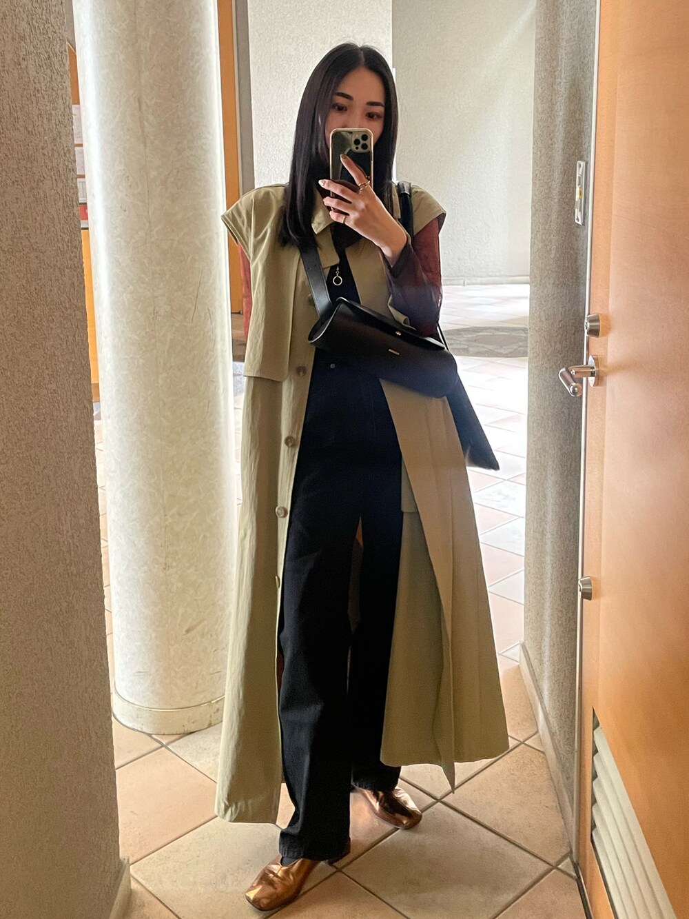 ゴールド系のパンプス、ブラック系のデニムパンツ、ブラック系のショルダーバッグを着用したレディースの春コーディネートの3枚目の写真