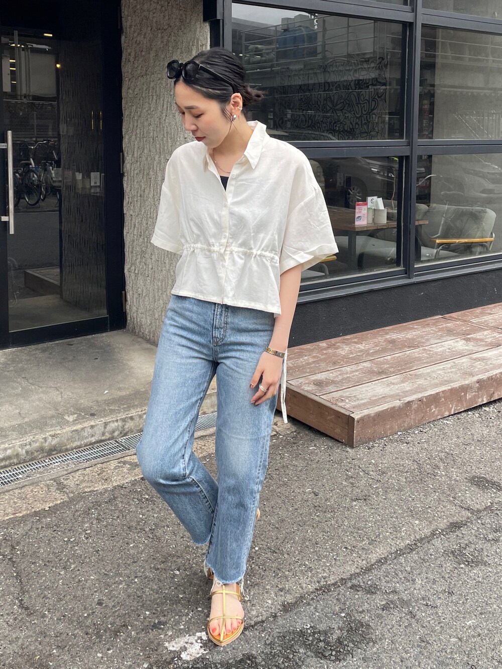 ブルー系のデニムパンツ、ゴールド系のサンダル、ホワイト系のシャツ/ブラウスを着用したレディースの春コーディネートの3枚目の写真