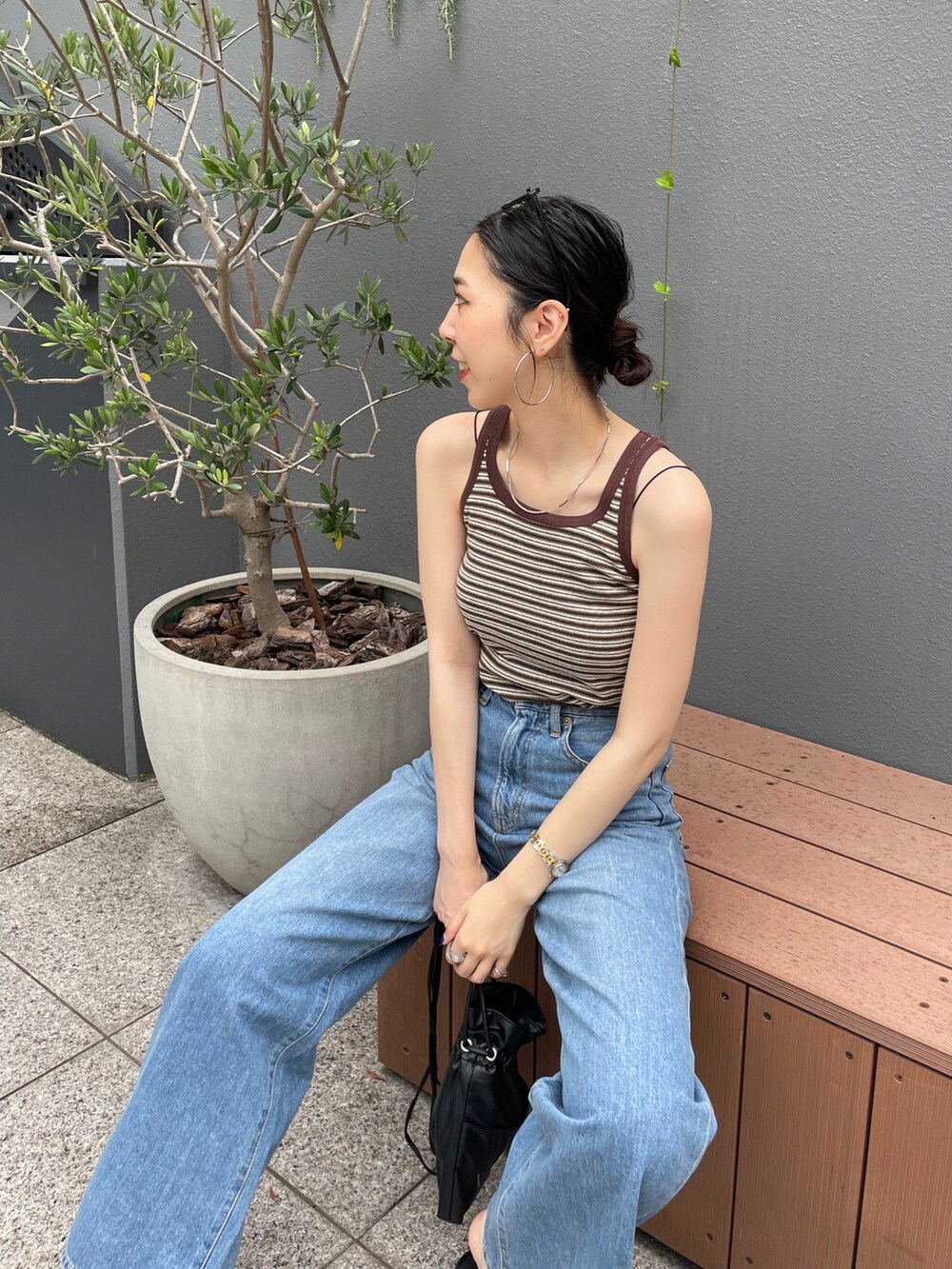 ブラック系のショルダーバッグ、ブラウン系のタンクトップ、ブルー系のデニムパンツを着用したレディースの夏コーディネートの4枚目の写真